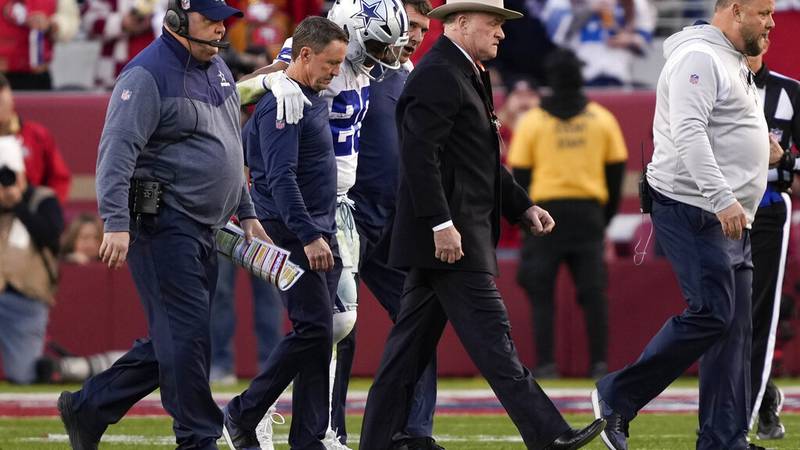 Dallas Cowboys running back Tony Pollard, middle, is helped off the field next to head coach...