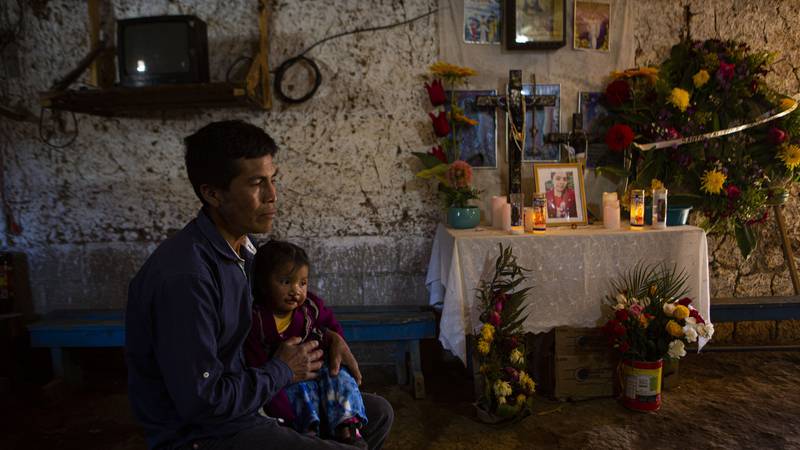 Ricardo Garcia and daughter Angela sit next to an altar adorned with photographs of his older...