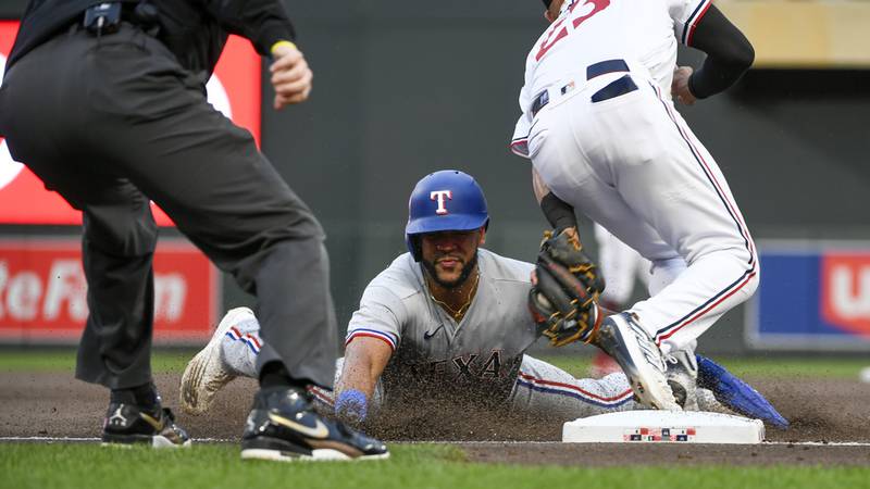 Texas Rangers Leody Taveras, center, is tagged out by Minnesota Twins third baseman Royce Lewis...
